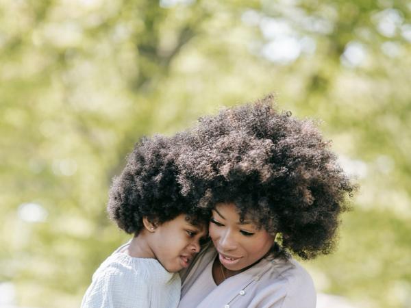 A mother cradles her young son in a tender embrace outdoors