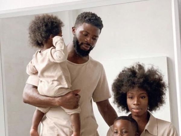 A young family in matching cream poses together in a mirror portrait