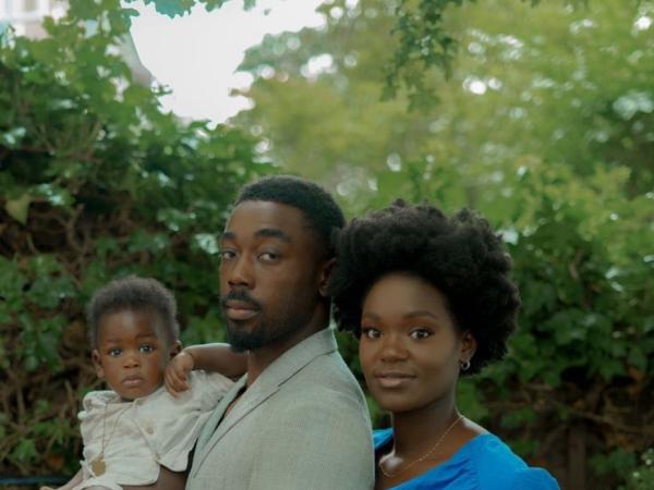 A young family stands for a formal garden portrait, mother holding flowers