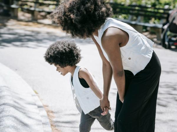 A mother and son pause on a park path to retie their shoes